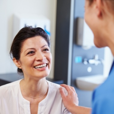 Woman smiling at dentist during dental implant consultation