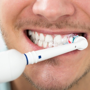 close-up of a man brushing his teeth with an electric toothbrush