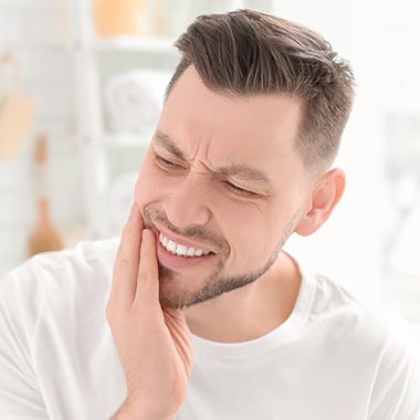 Man in need of restorative dentistry holding jaw