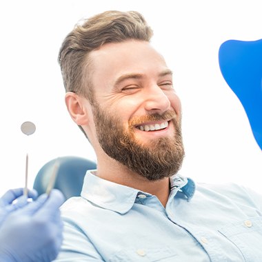 Man examining his smile after full mouth reconstruction