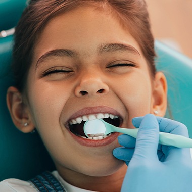 Dentist checking child's smile after silver diamine fluoride treatment
