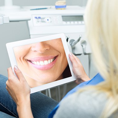 Woman looking at virtual smile design on tablet computer