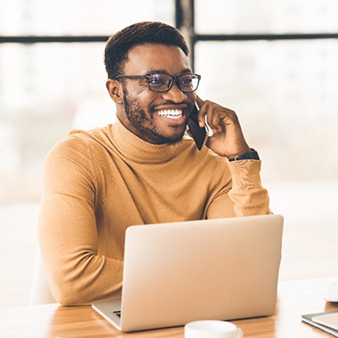 smiling person sitting at a desk and talking on the phone