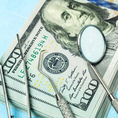money and dental tools representing cost of dental emergencies in Avon