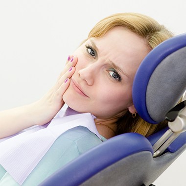 Woman in need of tooth extraction holding cheek