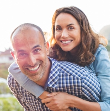 Man and woman smiling after dental implant tooth replacement