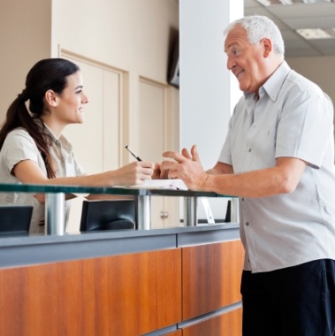 Man checking in at front desk for dental implant consultation