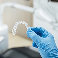 Invisalign dentist in Avon holding a clear aligner