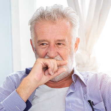 Man who needs to replace missing teeth covering his smile