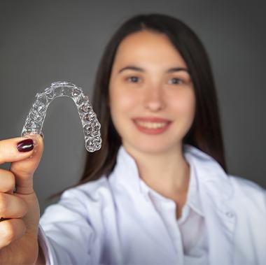 Woman holding up Invisalign tray