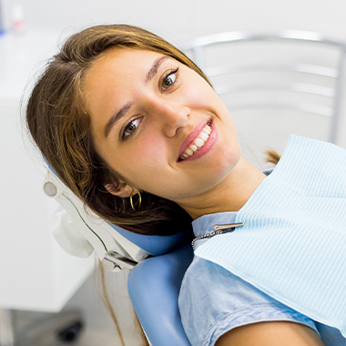 Smiling woman in dental chair after receiving antibiotic therapy
