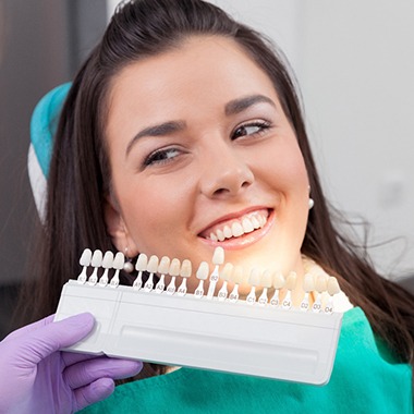A dentist comparing veneer shades with a patient’s smile.