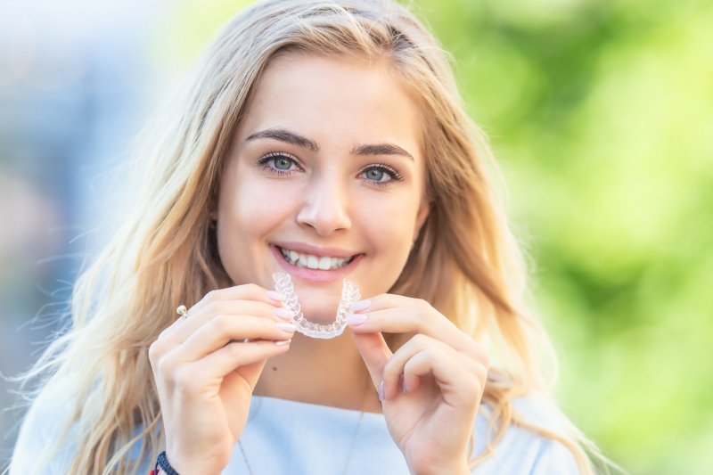 young woman holding an Invisalign aligner